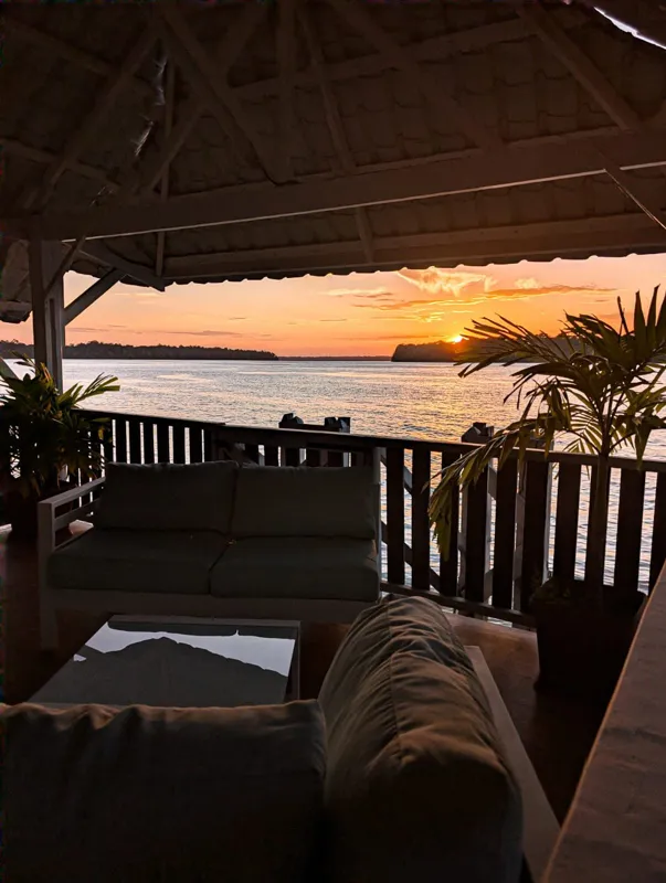 Salon couvert avec canapés, face au fleuve au coucher du soleil